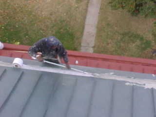 Roof Menders crew member embedding mesh into base acrylic